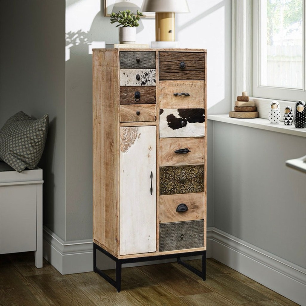 Komoda WESTPORT w stylu industrialnym, wykonana z litego drewna mango, z patchworkowymi frontami w różnych wykończeniach, stojąca w jasnym, nowoczesnym wnętrzu przy oknie.