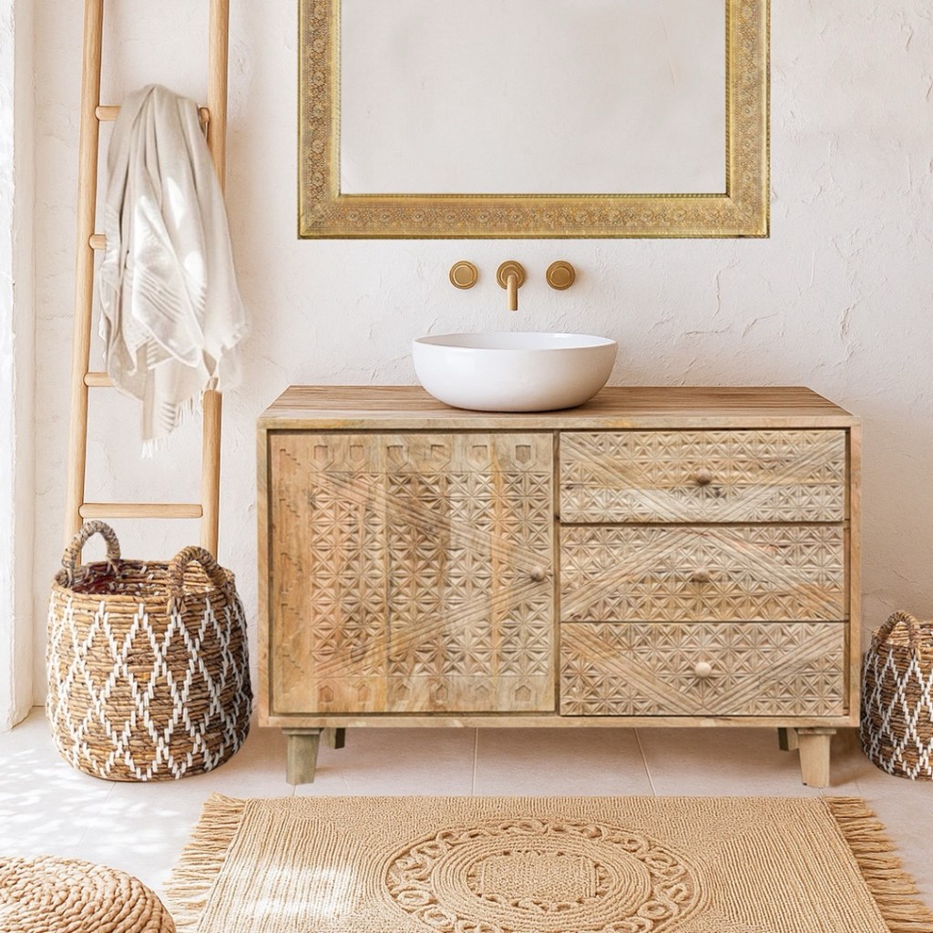 Niska komoda Boho Chic z rzeźbionego drewna mango, ustawiona w jasnej łazience lub sypialni w stylu boho. Obok naturalne dodatki – kosze, pleciony dywan i drabinka na ręcznik.