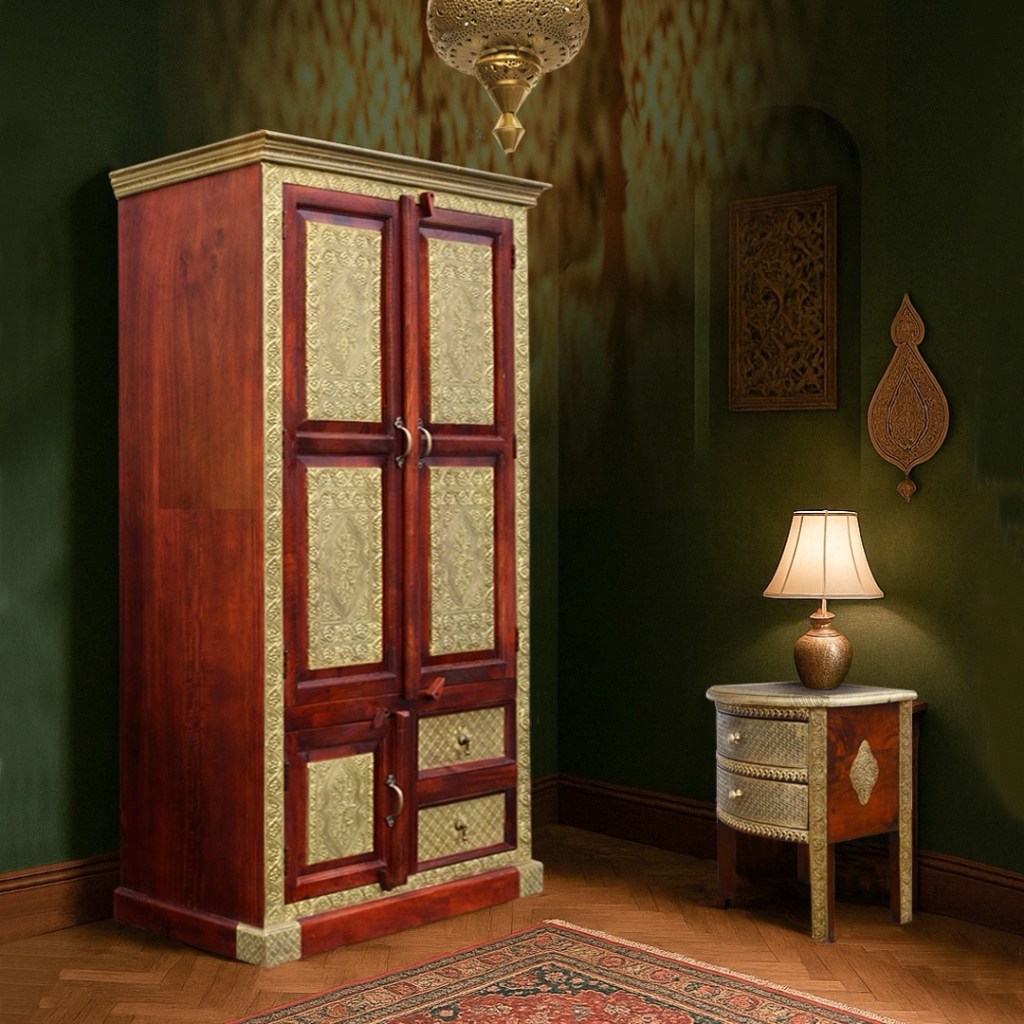 Orientalna szafa Bindi z drewna i mosiądzu w bogato zdobionym wnętrzu w stylu indyjskim. Obok nocna szafka z lampą, ciemnozielone ściany i orientalne dekoracje ścienne. Produkt Karina Meble.