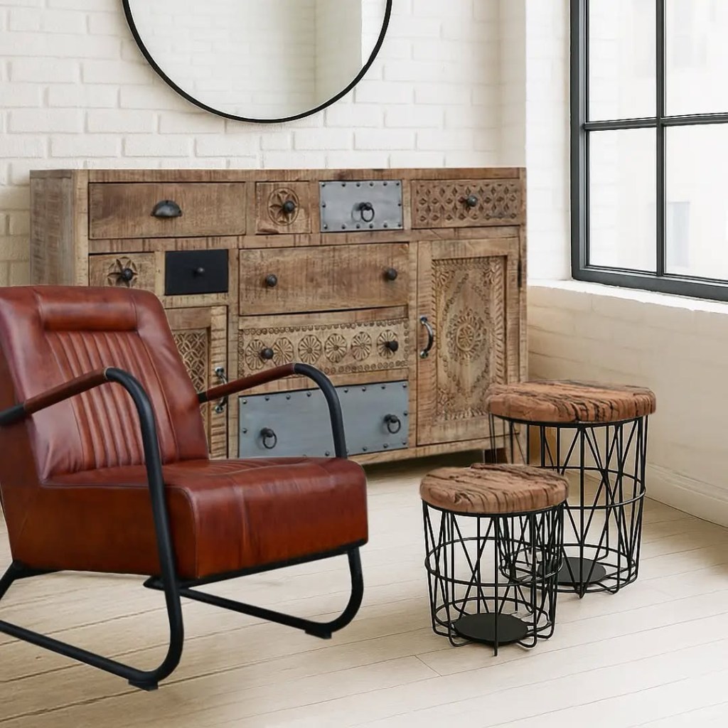 Komoda CHAKRA z litego drewna mango i metalowymi wstawkami w stylu loftowym, ustawiona w industrialnym wnętrzu z brązowym fotelem i stolikami z drewnianymi blatami.