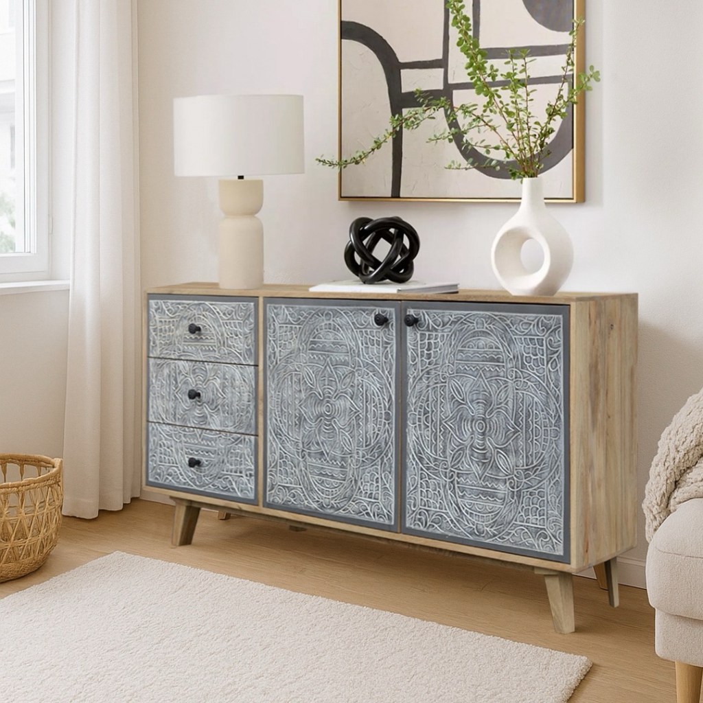 Komoda Lumi z litego drewna mango z trzema szufladami i dwoma szafkami. Fronty szafek oraz szuflad są ręcznie rzeźbione w geometryczny wzór, typowy dla stylu indyjskiego i boho. Mebel stoi w jasnym, nowoczesnym salonie.